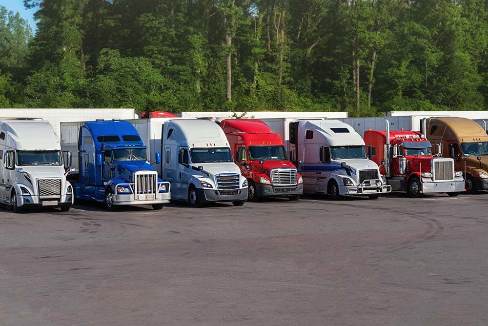 Semi trucks parked side by side in an outdoor parking lot